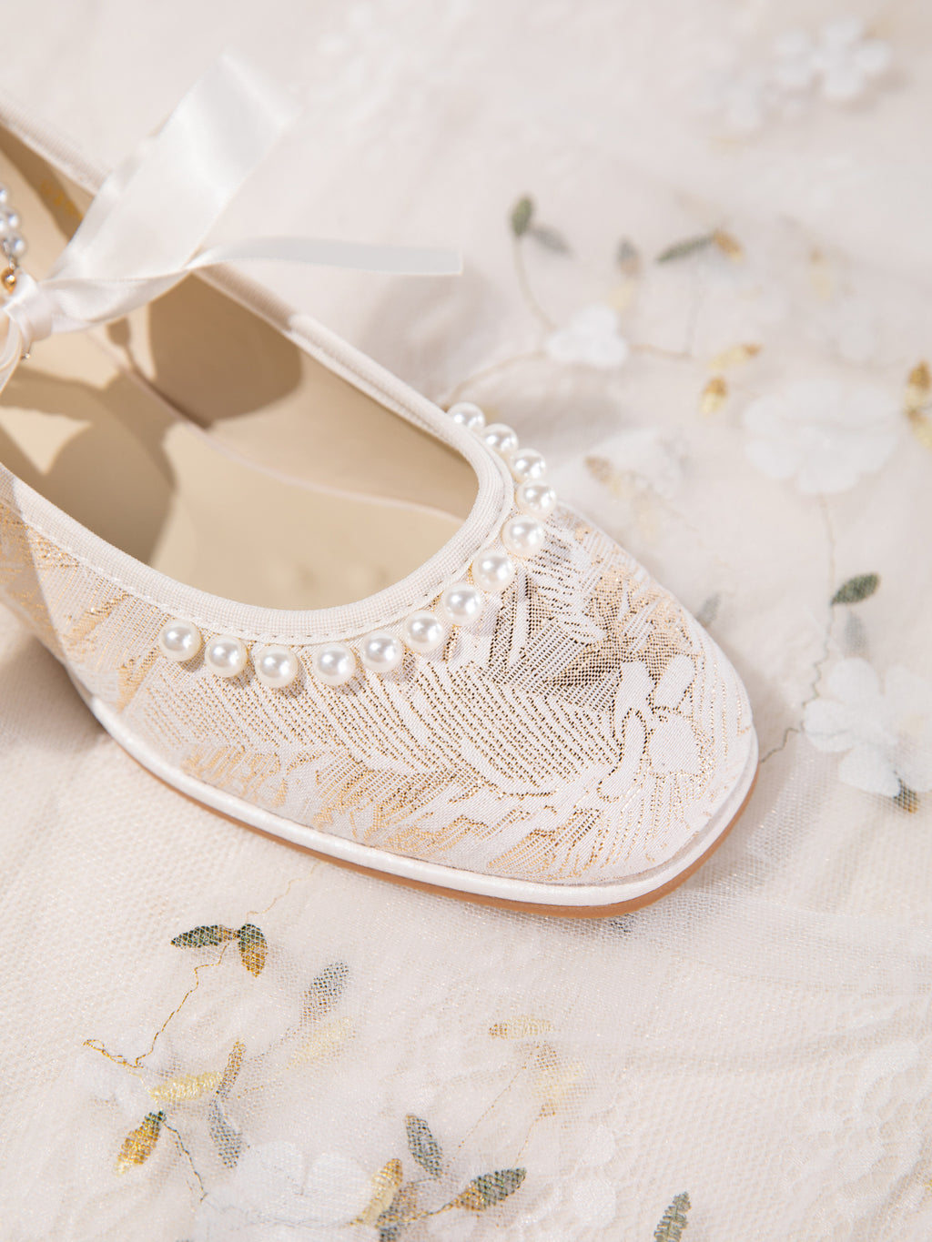 Top-down view of pearl toe cap detail on champagne flats