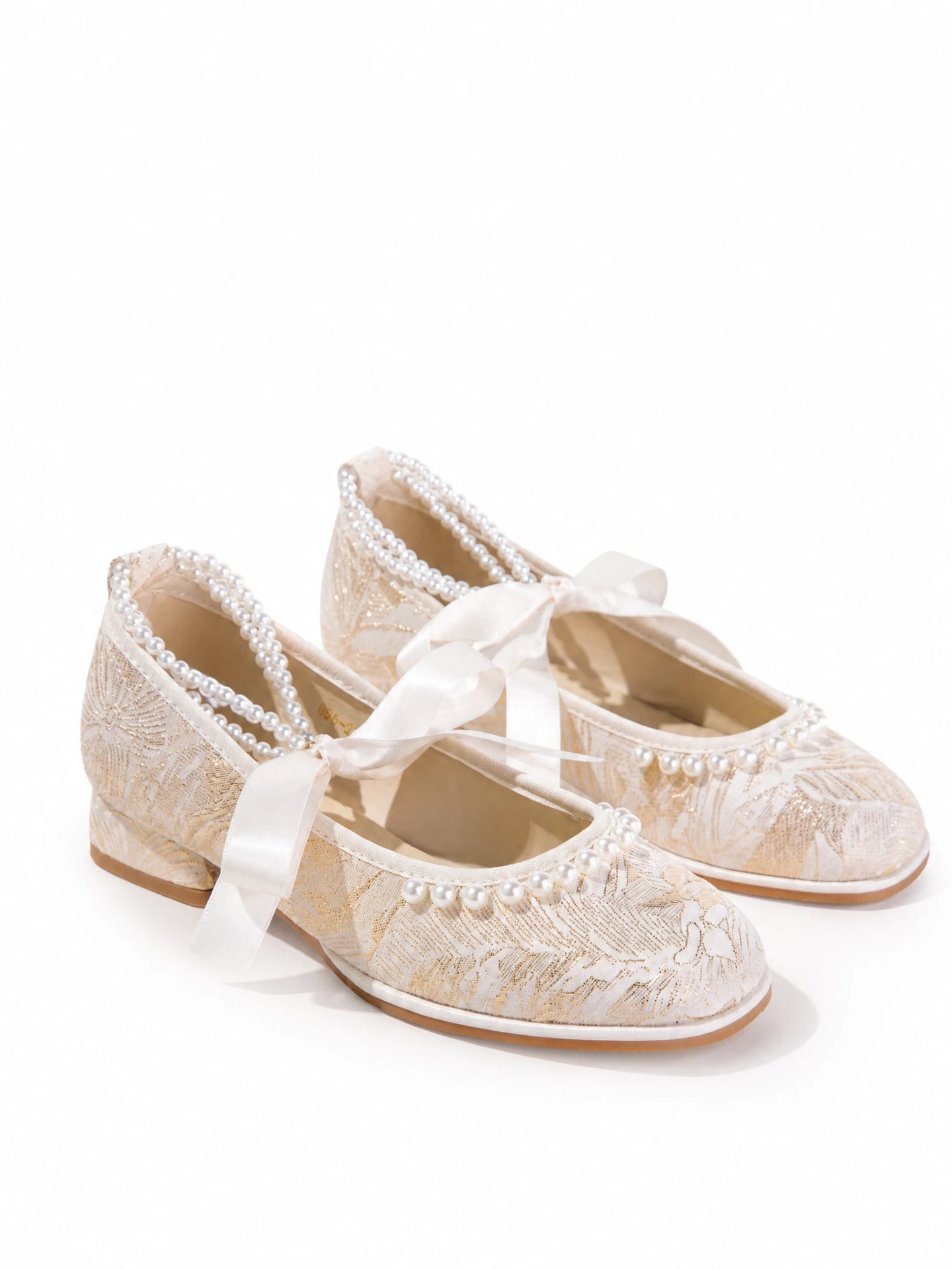 Close-up of pearl strap and cream jacquard floral brocade pattern